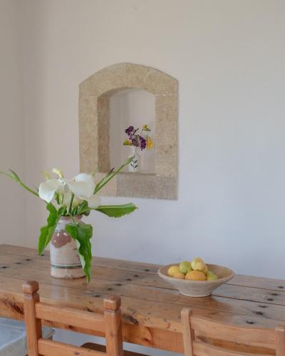 a table with a vase of flowers and a bowl of fruit at Borantza stone house in Aroniadika