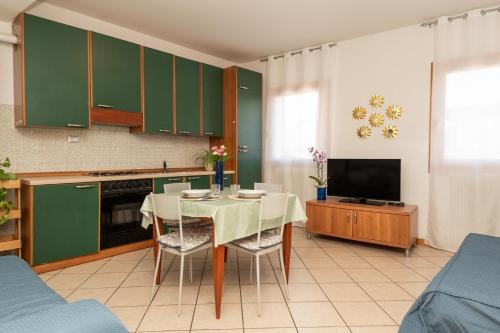 a kitchen with a table and a kitchen with green cabinets at Ca di Mar 4 in Caorle