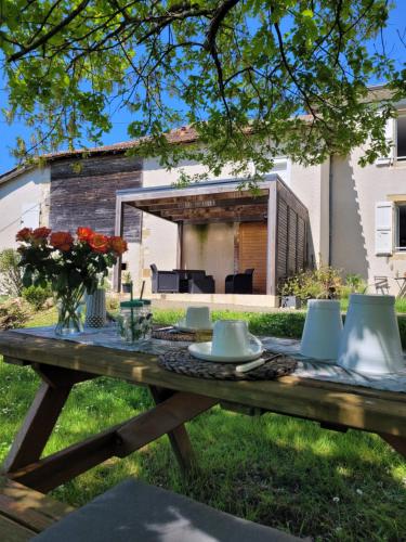 a wooden picnic table in the grass with flowers on it at La Gurlanne in Lasséran