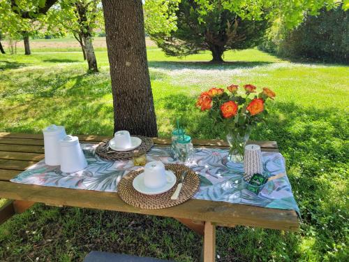 a picnic table with plates and a vase of flowers at La Gurlanne in Lasséran