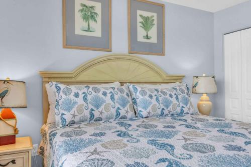 a bed with blue and white sheets and two pictures on the wall at Family-Friendly Oceanfront Condo at Compass Cove Resort in Myrtle Beach in Myrtle Beach