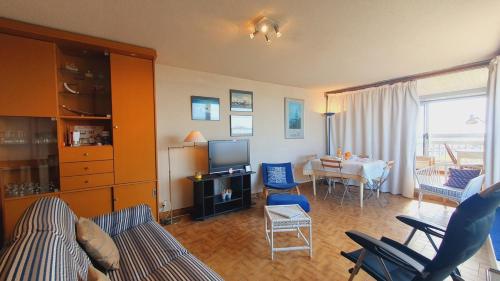 un salon avec un canapé, des chaises et une télévision dans l'établissement L'Anémone Roof Top Parking Clim Wi-Fi - ROSSIconciergerie - Linge inclus, à La Grande Motte