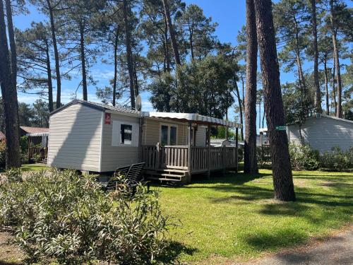 Cette petite maison blanche possède une terrasse couverte dans une cour. dans l'établissement Prix dégressif - Bungalow 4-6 personnes aux Dunes de Contis, à Saint-Julien-en-Born