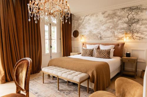 a bedroom with a large bed and a chandelier at Château Léognan, Domaine viticole - proche Bordeaux in Léognan