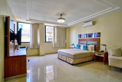 a bedroom with a bed and a tv and a couch at Hotel Libertad at historic main street in Santo Domingo