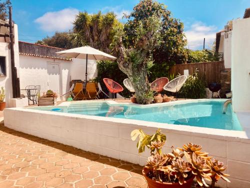 a swimming pool with chairs and an umbrella in a yard at Estrela do Corval in São Pedro do Corval