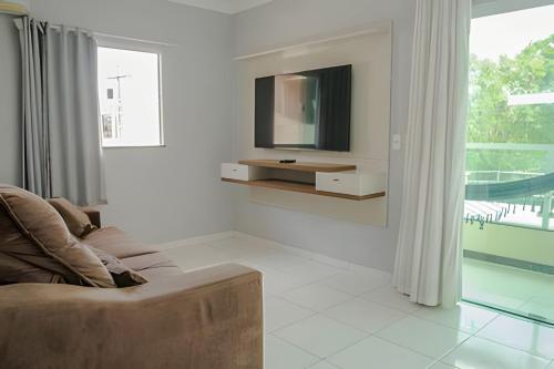 a living room with a couch and a tv on a wall at 500m PRAIA de Taperapuan; 2 quartos; WiFi 300mbs; 2 pavimento; Churrasqueira; Chuveirão; Estacionamento Gratuito 1 carro in Porto Seguro