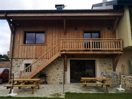 une maison avec une terrasse et deux tables de pique-nique dans l'établissement petit gîte des Marolais, à Mont-Saxonnex