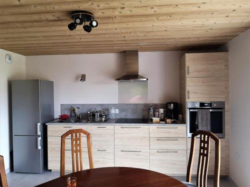 une cuisine avec un plafond en bois et une table dans l'établissement petit gîte des Marolais, à Mont-Saxonnex