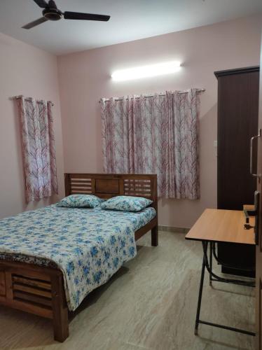 a bedroom with a bed and a table and windows at VILLA VISTA Apt RENTAL in Alleppey