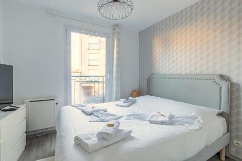 une chambre blanche avec un lit avec des serviettes dessus dans l'établissement 14-Le T2 de Shirley, à Montévrain