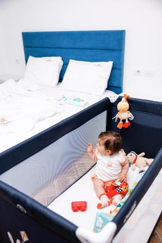 a baby sitting on a bed with toys at CAPTAIN'S RESIDENCE in Ksamil