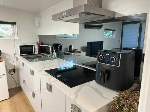 a kitchen with white cabinets and a black counter top at South London - Luxury Urban Cabin Retreat in Sutton