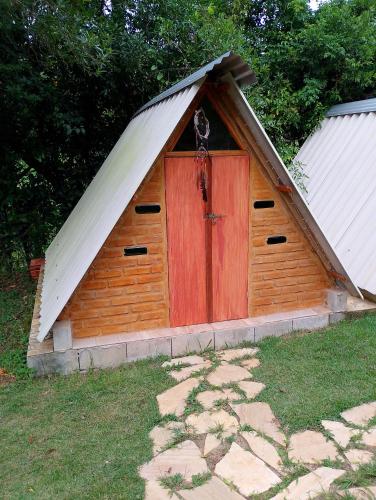 a small wooden doghouse with a red door at Recanto Vale da Lua in Passa Quatro