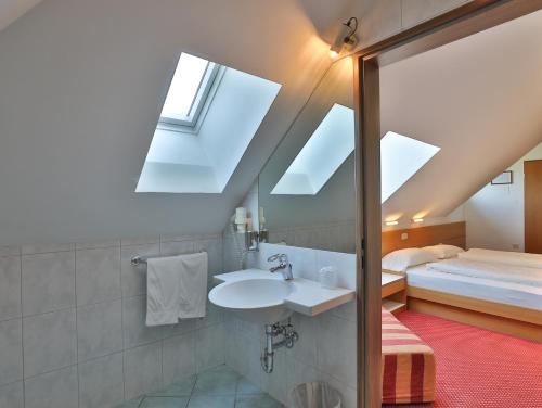 a bathroom with a sink and a bed with skylights at Hotel Sparerhof in Vilpiano
