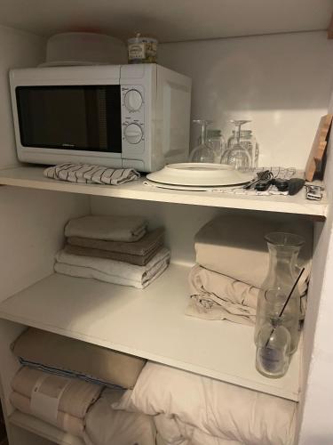 - un four micro-ondes installé au-dessus d'une étagère avec des serviettes dans l'établissement Maison aigues-mortaise dans la cité, à Aigues-Mortes