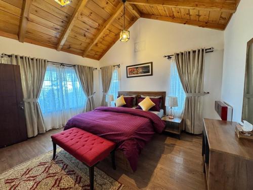 a bedroom with a large bed and a red bench at Haven Lodge Khaira Gali - Pine Ridge Residences #7 in Khaira Gali