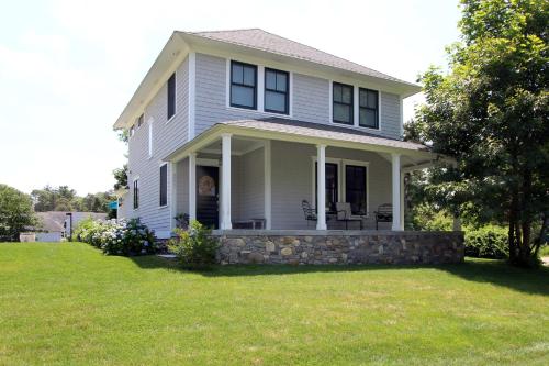 a white house with a stone wall at Pocasset Village Charmer in Pocasset