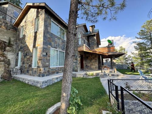 a large stone house with a tree in front of it at Haven Lodge Khaira Gali - Pine Ridge Residences #7 in Khaira Gali