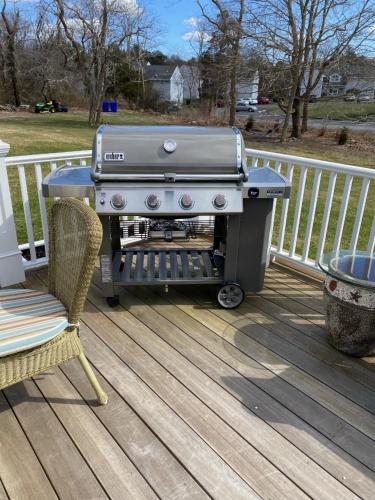 a grill sitting on a deck with a chair at Pocasset Village Charmer in Pocasset
