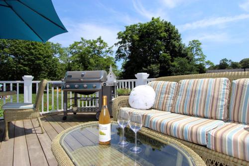 a patio with a couch and a grill with wine glasses at Pocasset Village Charmer in Pocasset