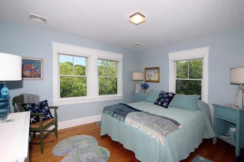 a bedroom with a bed and two windows at Pocasset Village Charmer in Pocasset