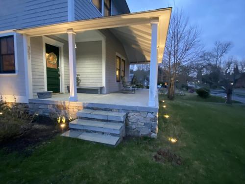 a house with a porch with lights on the grass at Pocasset Village Charmer in Pocasset