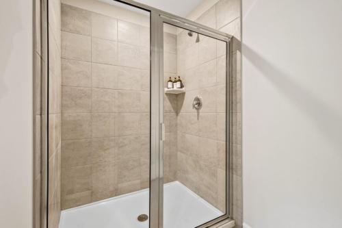 a shower with a glass door in a bathroom at Price Cut, New Lux Home 5 mins to Airport , 15 min to Downtown, 25 min to Buckhead with 3 beds and 3 baths in Atlanta