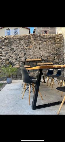une table en bois avec deux chaises et un mur en pierre dans l'établissement Chez Louis, à Saint-Flour