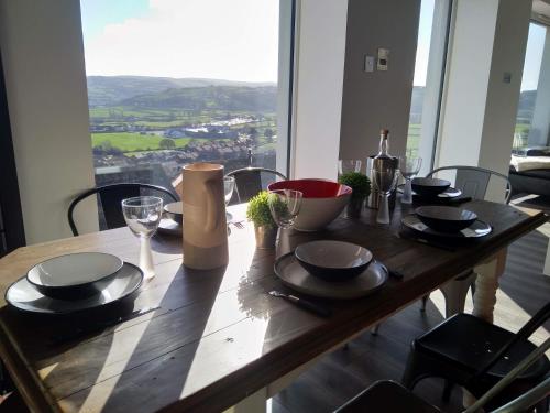 a wooden table with plates and wine glasses on it at Detached with Amazing Sea Views and Hot Tub in Llandudno