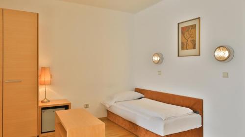 a small bedroom with a bed and a table at Hotel Sparerhof in Vilpiano