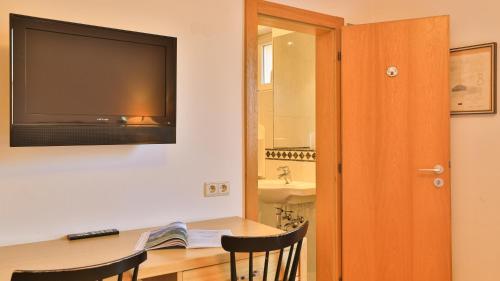 a room with a table with a television on the wall at Hotel Sparerhof in Vilpiano