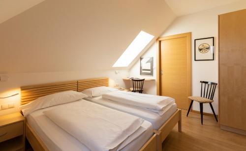 a bedroom with a large white bed with a skylight at Hotel Sparerhof in Vilpiano