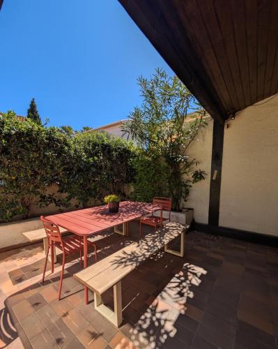 - une table de pique-nique et des chaises sur la terrasse dans l'établissement Maison de vacances - 4 chambres - Portiragnes-Plage, à Portiragnes