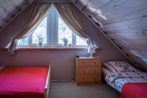 a attic bedroom with two beds and a window at Rodzinny zakątek - Noclegi w Bieszczadach - jacuzzi in Myczkowce