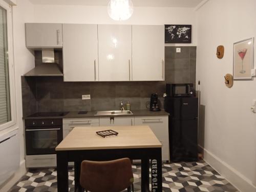 une cuisine avec des armoires blanches, une table et un évier dans l'établissement la loge sparnacienne, à Épernay