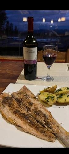 a plate of fish and a bottle of wine and a glass at Hotel boutique Pukarainca in Uspallata