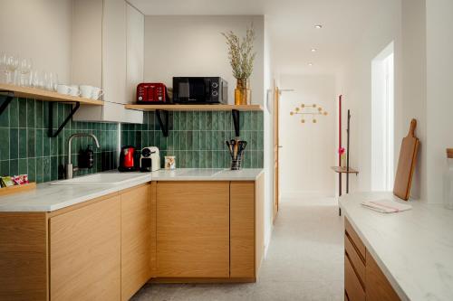 une cuisine avec des placards en bois et du carrelage vert dans l'établissement Beauquartier - Champs-Elysées, à Paris