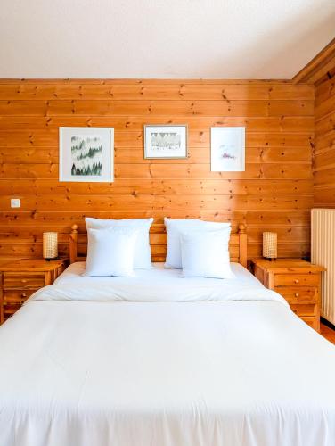 a bedroom with a white bed with wooden walls at Centered Ski/Swim Ap. w/ private yard & fireplace in Anzère