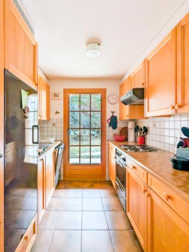 a kitchen with wooden cabinets and a large window at Centered Ski/Swim Ap. w/ private yard & fireplace in Anzère