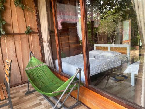a hammock on a porch with a bed in a window at FOREST BREATH ECO-LODGE in Tân Phú