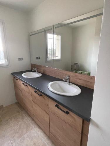 une salle de bain avec deux lavabos et un grand miroir dans l'établissement Paradis du Sud, à Salazac