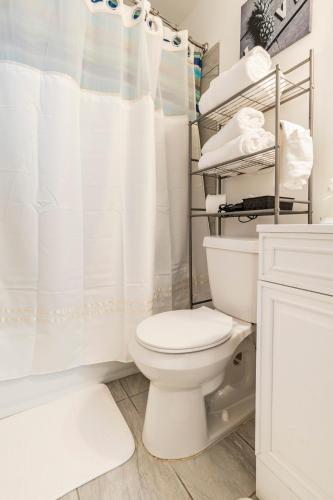 a white bathroom with a toilet and a shower at Cozy Private Entry Apt with a Full-Size Kitchen in Orlando