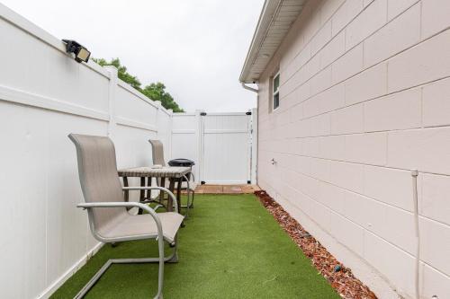 a patio with chairs and a table and a white wall at Cozy Private Entry Apt with a Full-Size Kitchen in Orlando