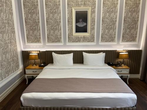 a bedroom with a large white bed with two night stands at Theatrum Hotel Baku in Baku