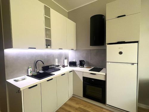 una piccola cucina con armadietti bianchi e frigorifero di GREEN Apartment 2 a Poznań