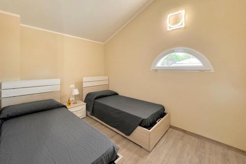 a bedroom with two beds and an arched window at Borgo Del Navigatore in Marina di Grosseto
