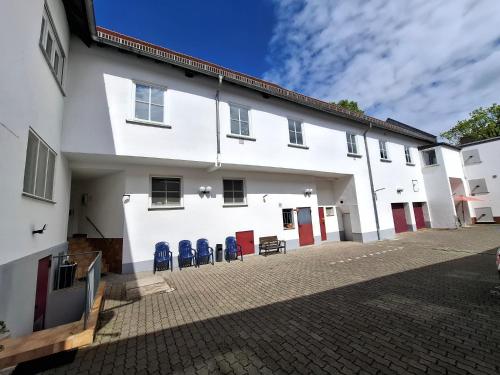 a white building with blue chairs in the courtyard at Landhotel Solmser Hof GbR in Echzell