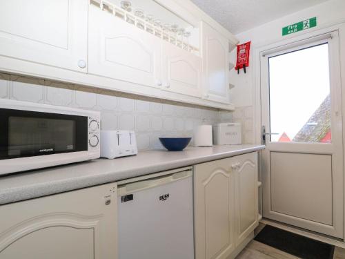 a kitchen with white cabinets and a microwave at Chalet 58 - The Beach House in Deal