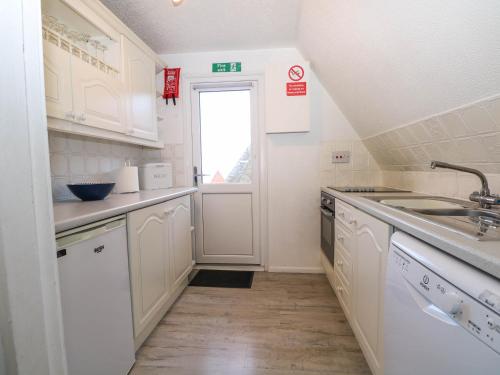 a kitchen with white cabinets and a sink and a window at Chalet 58 - The Beach House in Deal